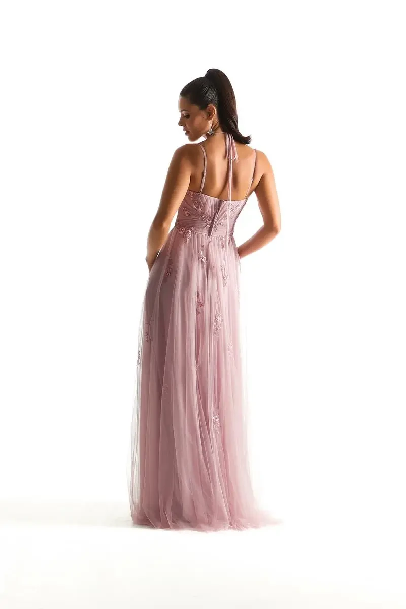 Model is wearing a desert rose English Net bridesmaid dress with a pleated scoop neckline, floral appliqués, and double straps that tie at the back.