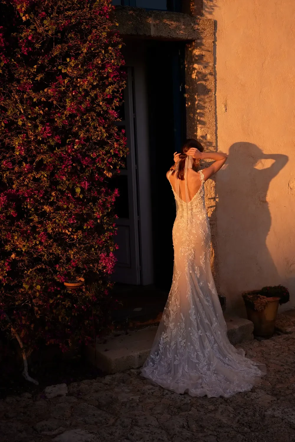 model is wearing an open back lace bridal gown