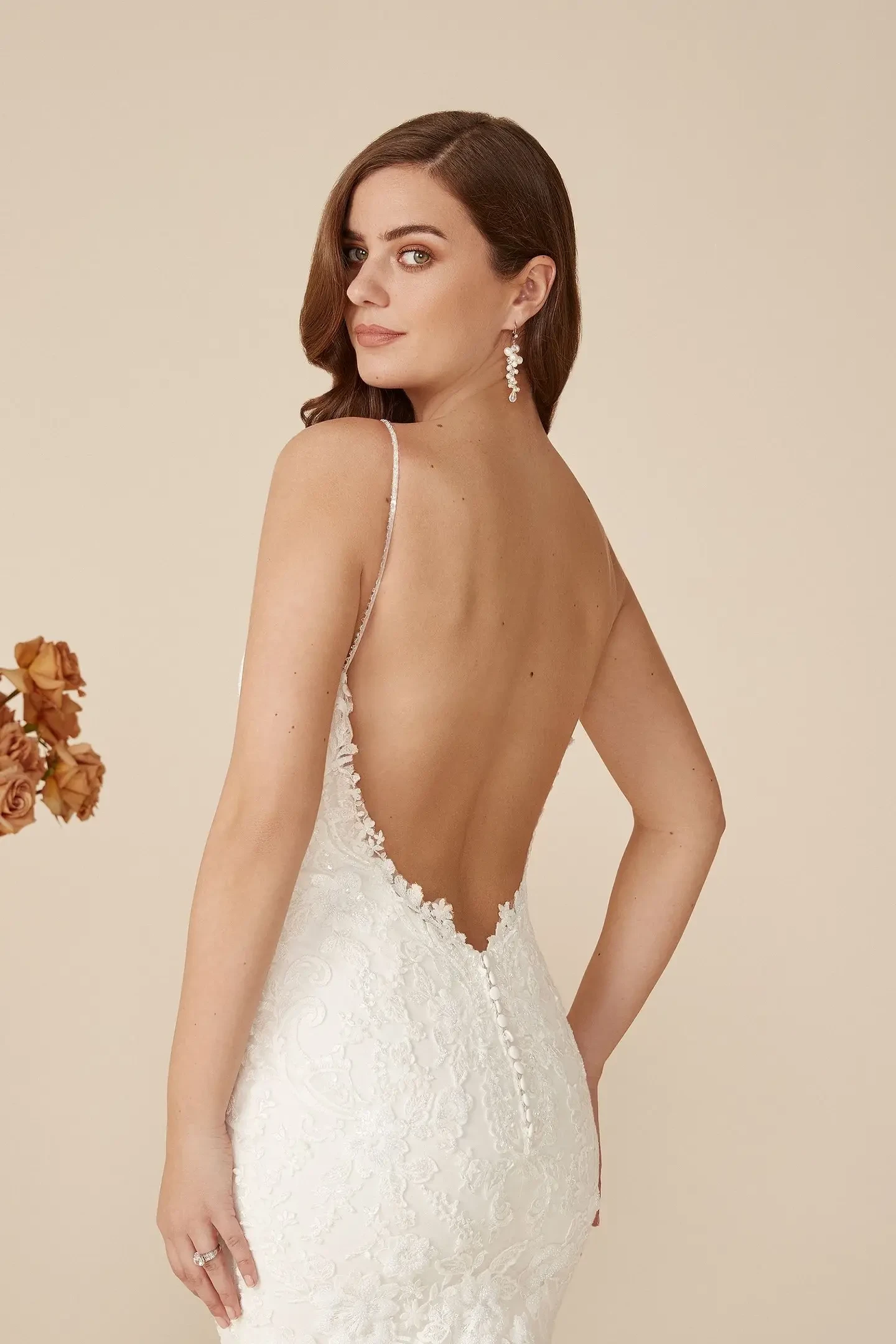 Model is wearing a sparkling fit and flare gown with beaded appliqués, glitter tulle, a low open back, and a scalloped lace hem.