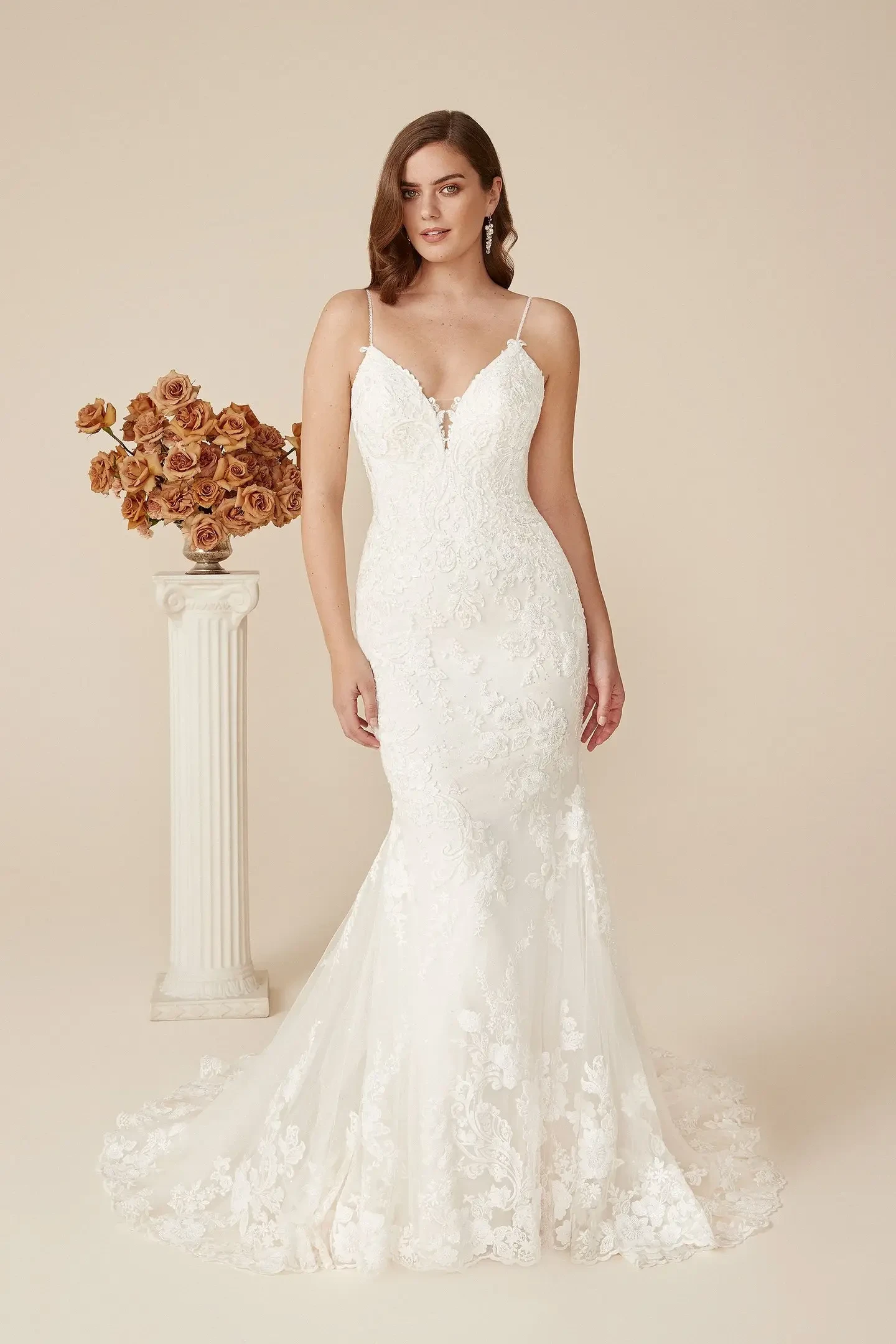 Model is wearing a sparkling fit and flare gown with beaded appliqués, glitter tulle, a low open back, and a scalloped lace hem.