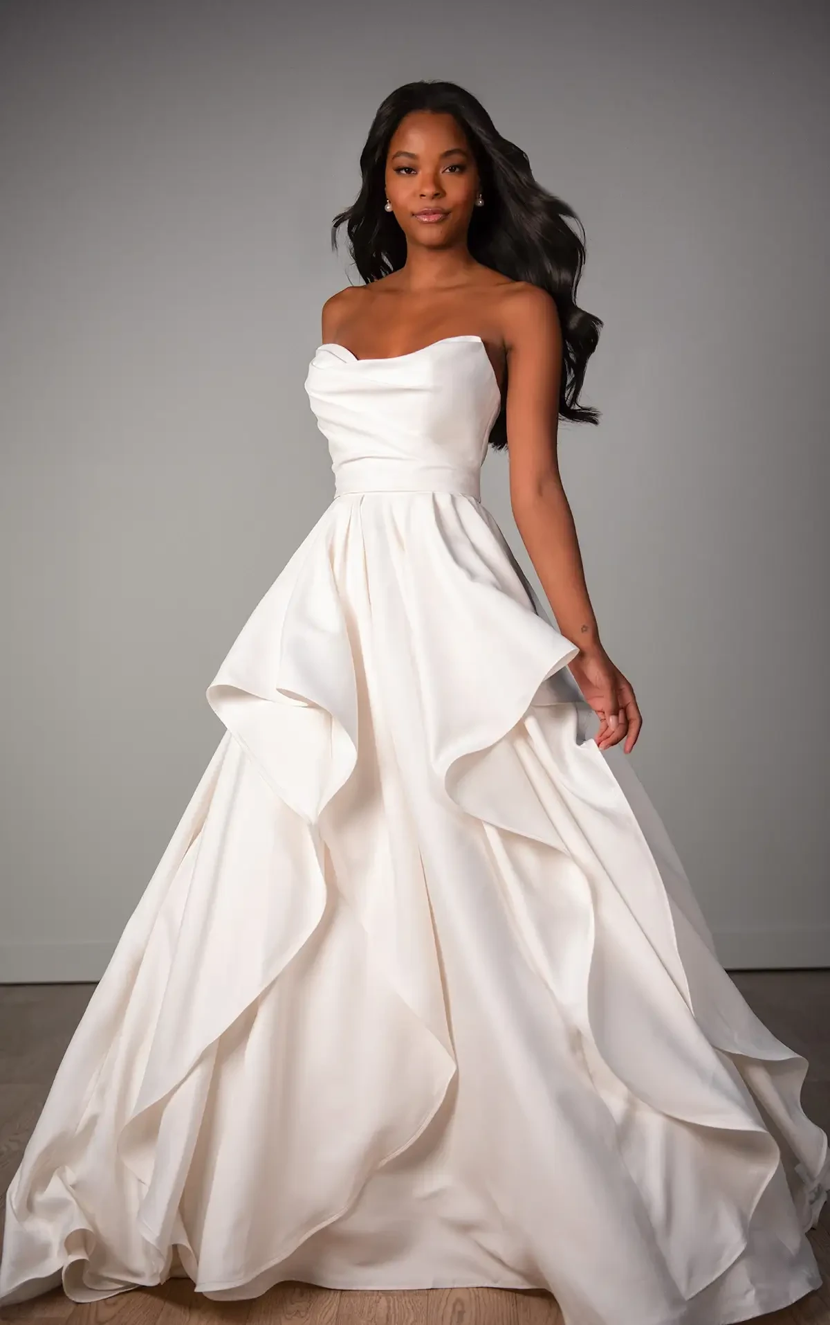 Model is wearing a strapless mikado bridal gown with a ruched bodice
