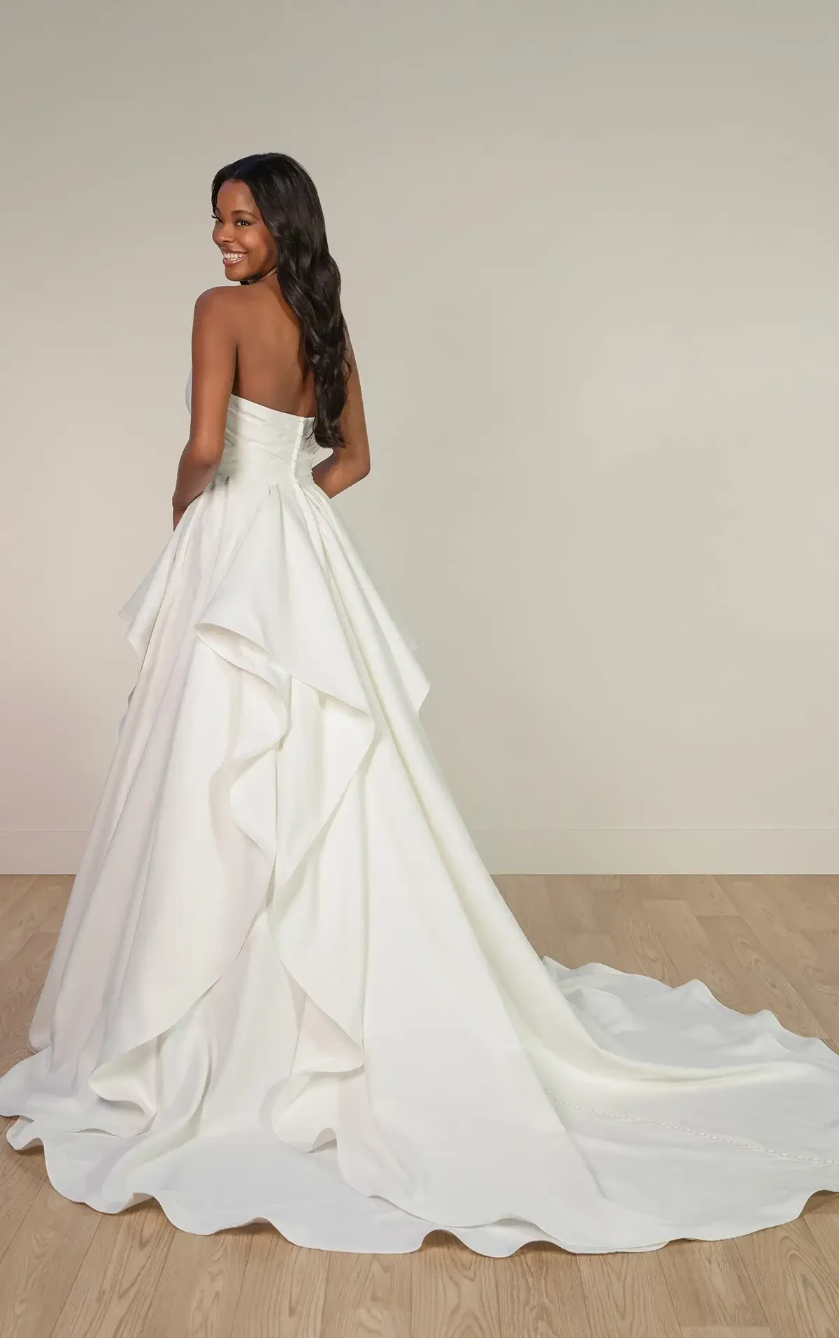 Model is wearing a strapless mikado bridal gown with a ruched bodice