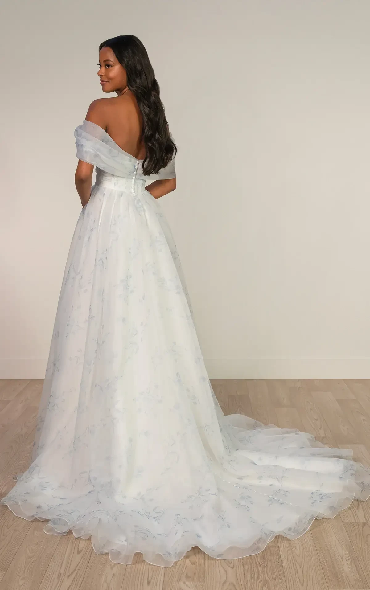 Model is wearing an organza off the shoulder a-line wedding dress with blue floral prints