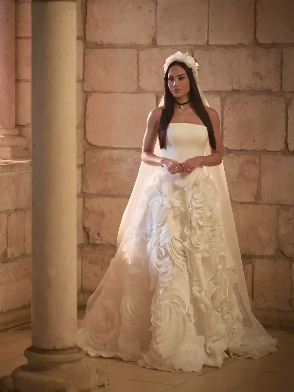 model is wearing a sleeveless bridal gown with a veil