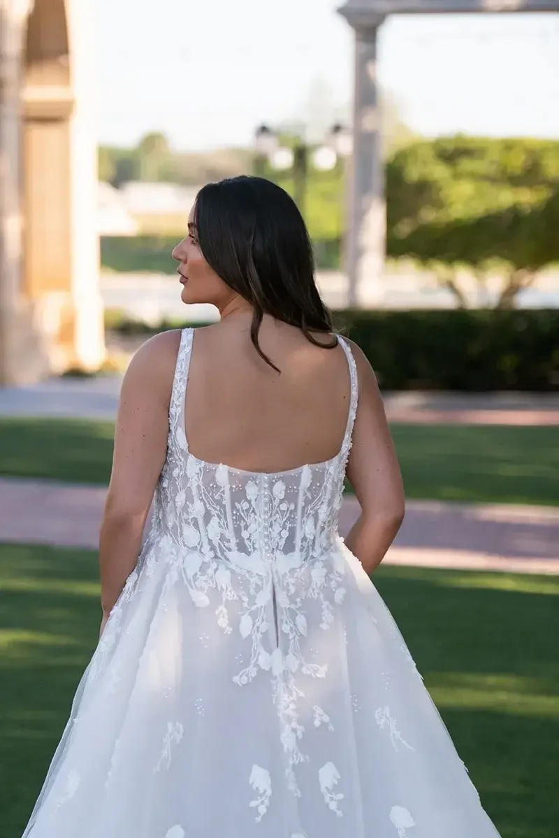 Model is wearing a plus size a-line wedding dress with 3D floral lace and a corset bodice by essense of australia 