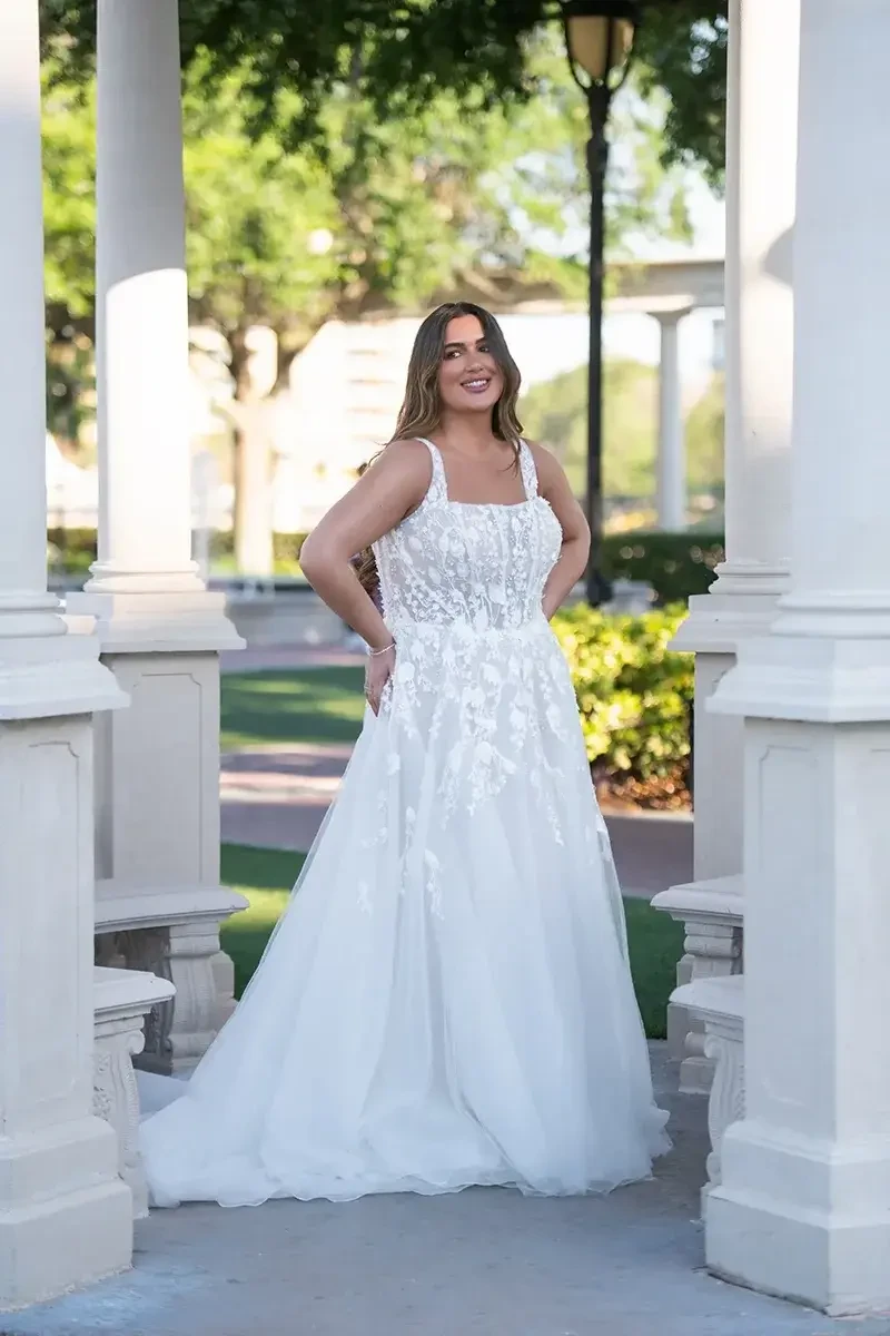 Model is wearing a plus size a-line wedding dress with 3D floral lace and a corset bodice by essense of australia 